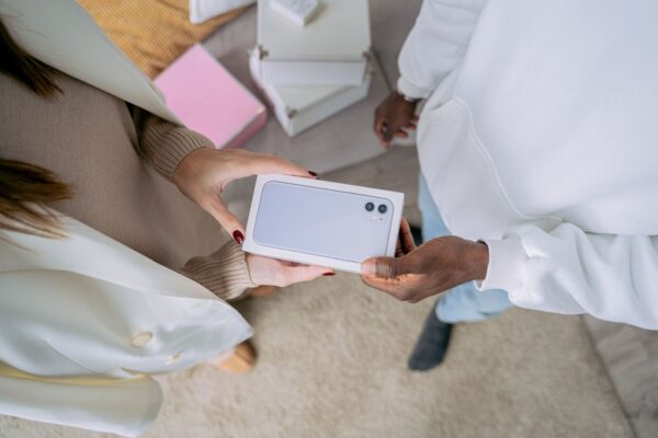 Två personer håller en förpackad smartphone med dubbla kameror