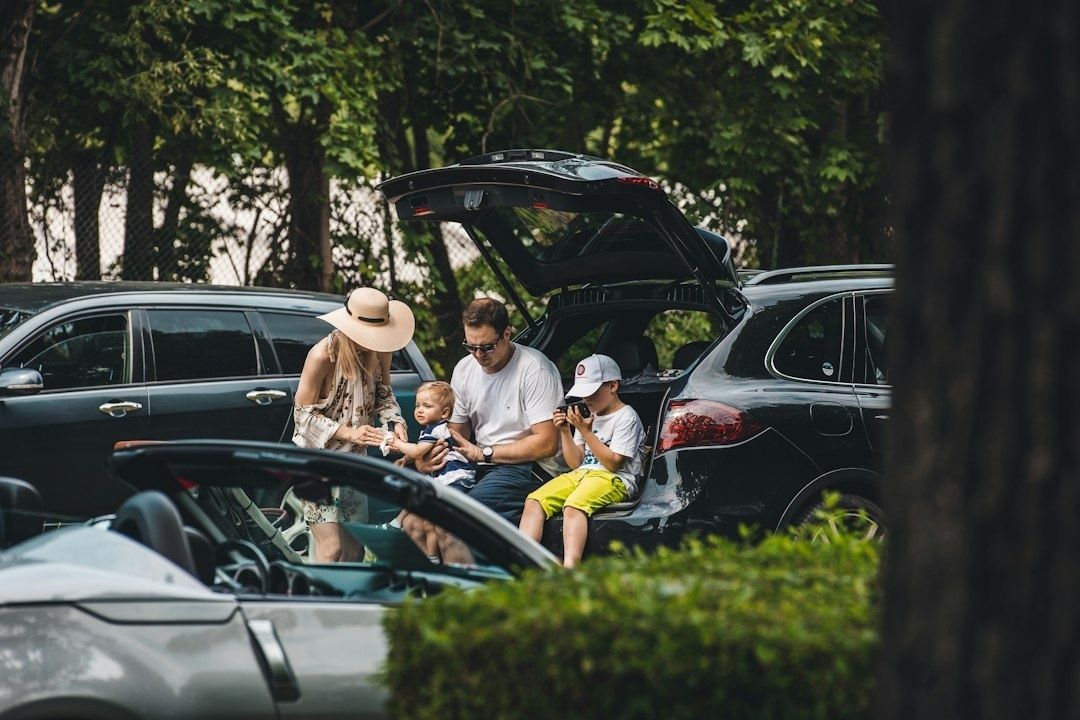 Familj samlas vid en bil med öppen baklucka på en parkering